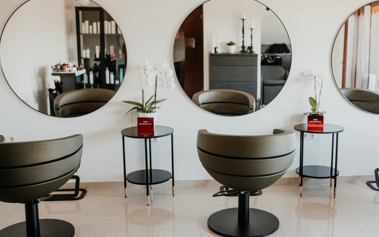 Ruhiger Salon mit Stühlen, Orchidee und runden Spiegeln
